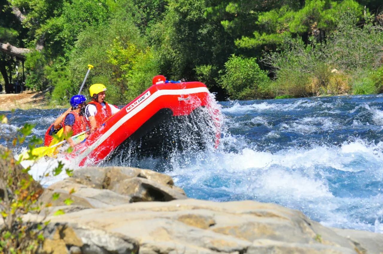 Köprülü Kanyon içinde rafting botunda kürek çeken can yelekli insanlar
