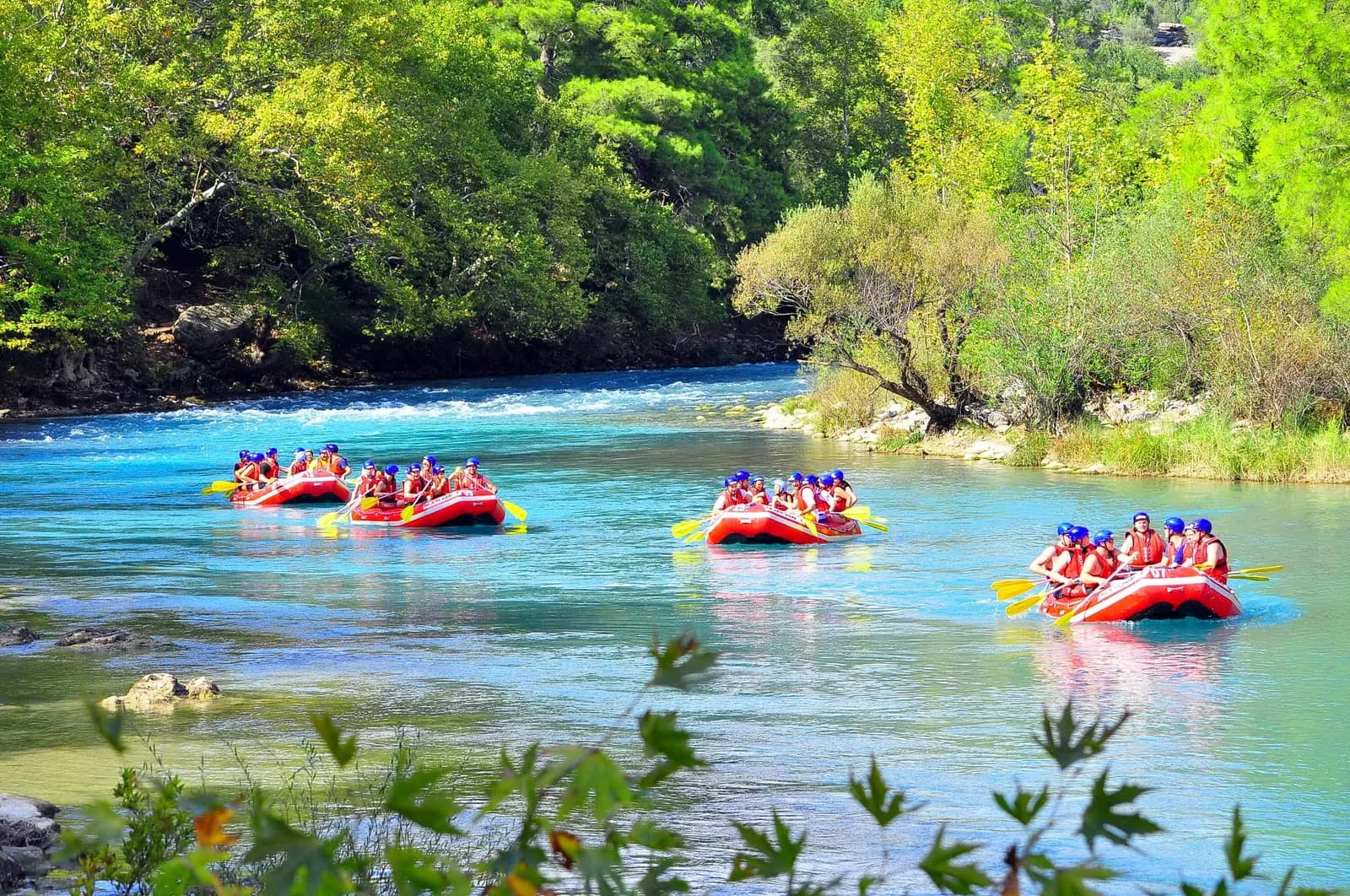Rafting turu sonrasında nehir kenarındaki masalarda yemek yiyen misafirler