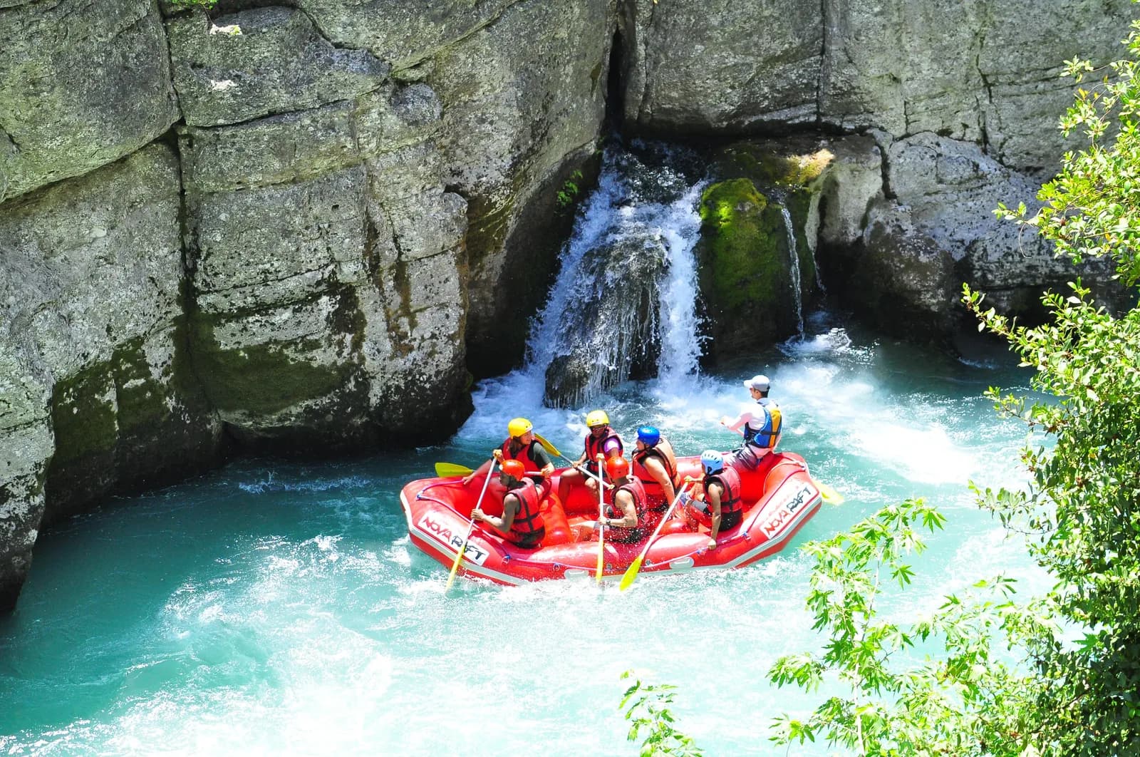 Köprülü Kanyon nehrinde can yelekli ve kasklı rafting katılımcıları botun kenarında