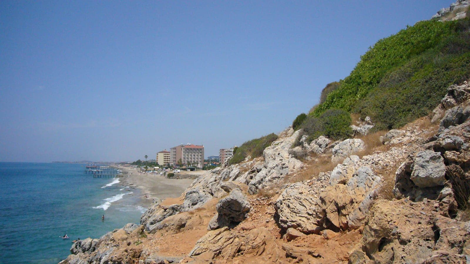 Breiter Sandstrand mit Badenden und dem Ort dahinter